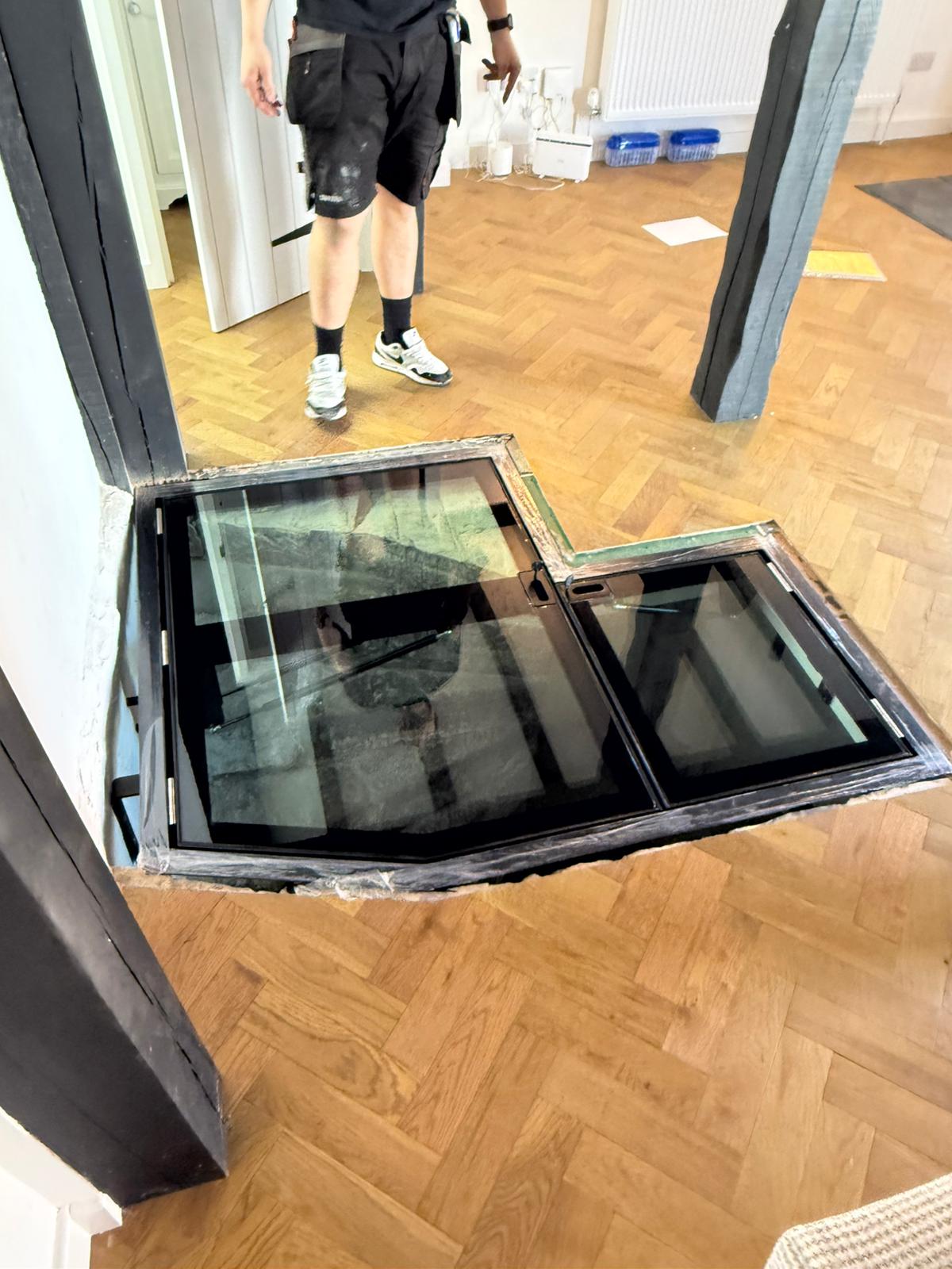 Bespoke L-shaped hinged glass double door floor open showing ancient stone staircase descent, period property Burwash East Sussex
